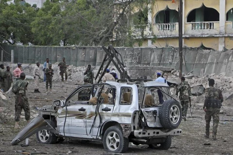 Binh sỹ Somali đứng gần đống đổ nát sau vụ tấn công bằng bom xe nhắm vào một trạm kiểm soát ở Mogadishu ngày 21/3. (Nguồn: AP)