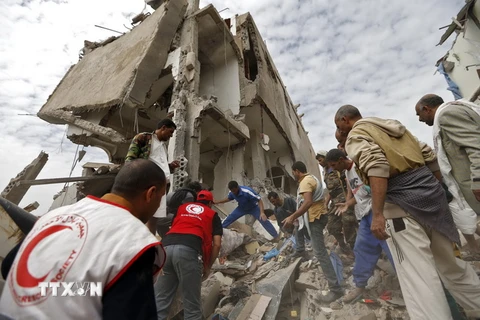 Người dân Yemen và nhân viên Chữ thập Đỏ tìm kiếm nạn nhân bị vùi lấp trong vụ không kích ở Sanaa ngày 25/8. (Nguồn: AFP/TTXVN)