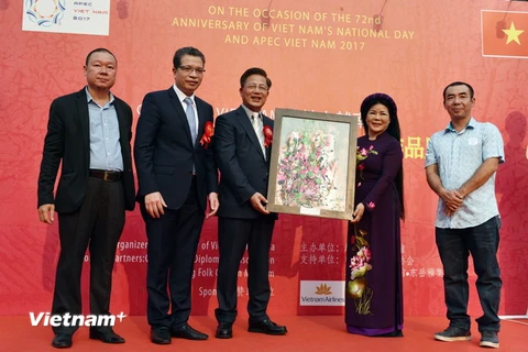 Họa sỹ Văn Dương Thành tặng tranh cho Hội Ngoại giao công chúng Trung Quốc. (Ảnh: Vĩnh Hà/Vietnam+)