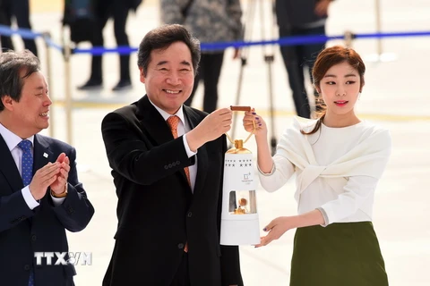 Thủ tướng Hàn Quốc Lee Nak-Yon (giữa) và nhà cựu vô địch trượt băng nghệ thuật Yuna Kim (phải) rước đuốc tại sân bay quốc tế Incheon ngày 1/11. (Nguồn: AFP/TTXVN)