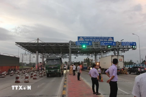 Lái xe tải Bình Định trả tiền lẻ để qua trạm BOT nam Bình Định ngày 14/11. (Ảnh: Phạm Kha/TTXVN)