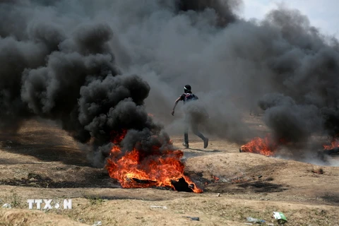 Người Palestine đốt lốp xe trong cuộc biểu tình tại khu vực biên giới Dải Gaza với Israel. (Nguồn: THX/TTXVN)