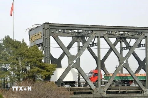 Xe chở hàng hóa di chuyển trên cây cầu hữu nghị Trung Quốc - Triều Tiên nhìn từ Đan Đông, Trung Quốc ngày 28/3. (Nguồn: Kyodo/TTXVN)