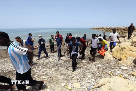 Người di cư tới bờ biển ở phía đông Tripoli, Libya sau khi được cứu trên biển ngày 29/6. (Ảnh: THX/TTXVN)