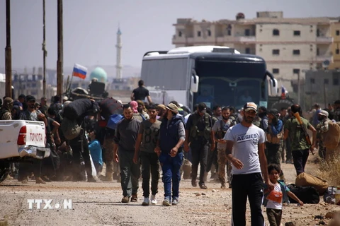 Các tay súng phiến quân cùng gia đình chuẩn bị rời thành phố Daraa để tới những khu vực do phe đối lập kiểm soát tại miền bắc Syria ngày 15/7. (Ảnh: AFP/TTXVN)