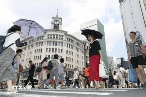 Người dân che ô tránh nắng tại Ginza, thủ đô Tokyo, Nhật Bản ngày 14/7. (Ảnh: Kyodo/TTXVN)