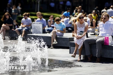 Người dân nghỉ ngơi tránh nóng tại đài phun nước quảng trường Tòa thị chính ở trung tâm London, Anh ngày 2/7. (Nguồn: AFP/TTXVN)