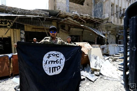 Một thành viên IS giương lá cờ chiến binh Hồi giáo ở thành phố cổ Mosul, Iraq ngày 10/7. (Nguồn: Reuters)