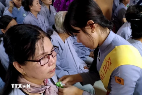 Nghi thức "Bông hồng cài áo" trong lễ Vu Lan ở Việt Nam. (Ảnh: Kim Há/TTXVN)