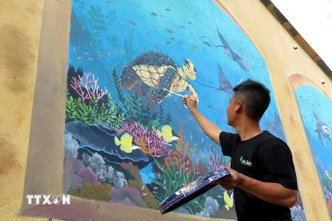 Các tình nguyện viên đang hoàn thiện những nét vẽ cuối cùng trên đảo Bé. (Ảnh: Phước Ngọc/TTXVN)
