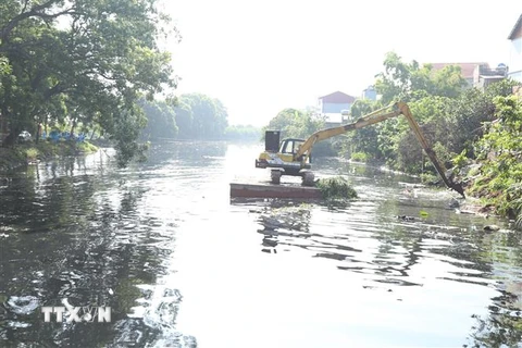 Phương tiện cơ giới tham gia múc bùn thải khơi thông dòng chảy sông Cầu Bây. (Ảnh: Mạnh Khánh/TTXVN)