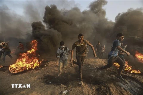 Người biểu tình Palestine chạy trốn làn đạn hơi cay của binh sỹ Israel trong xung đột tại khu vực biên giới với Dải Gaza ngày 28/9/2018. (Ảnh: THX/TTXVN)