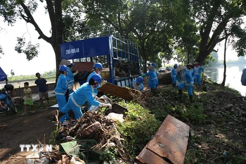 Công nhân vệ sinh môi trường đô thị Gia Lâm thực hiện thu gom rác thải bên bờ sông Cầu Bây. (Ảnh Mạnh Khánh/TTXVN)