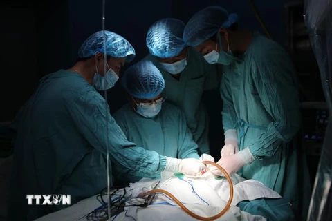 Các bác sỹ đang thực hiện ca phẫu thuật cho cháu bé. (Ảnh: Hồ Cầu/TTXVN)