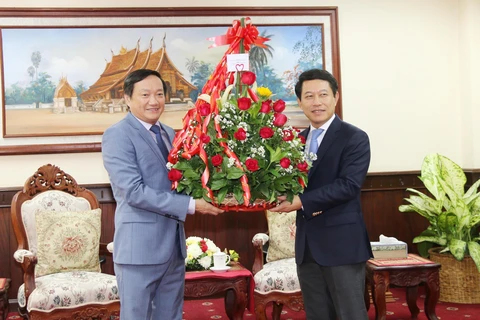  Đại sứ Việt Nam tại Lào Nguyễn Bá Hùng (trái) trao lẵng hoa chúc mừng năm mới cho Bộ trưởng Ngoại giao Lào. (Ảnh: Xuân Tú/TTXVN) 