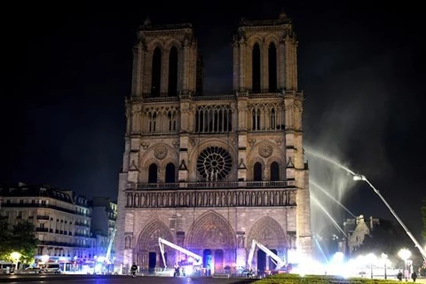 Lính cứu hỏa nỗ lực dập lửa tại hiện trường vụ cháy Nhà thờ Đức Bà ở Paris, Pháp tối 15/4/2019. (Ảnh: AFP/TTXVN)