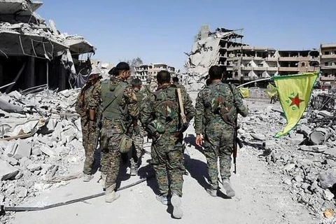 Các chiến binh của Lực lượng Dân chủ Syria đi ngang qua tàn tích của các tòa nhà bị phá hủy gần Bệnh viện Quốc gia sau khi Raqqa được giải phóng khỏi phiến quân IS ngày 17/10/2017. (Ảnh: Reuters)
