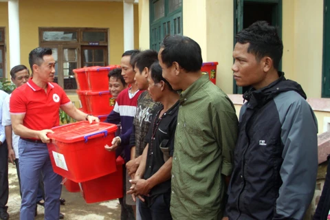 Ông Nguyễn Hải Anh - Phó Chủ tịch, Tổng Thư ký Hội Chữ thập đỏ Việt Nam trao tặng thùng đồ dùng gia đình cho các hộ gia đình. (Ảnh: Trịnh Bang Nhiệm/TTXVN)