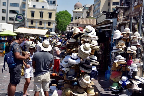 Khách du lịch mua mũ chống nắng tại Athens, Hy Lạp trong bối cảnh nhiệt độ lên tới 42 độ C. (Ảnh: AFP/TTXVN)