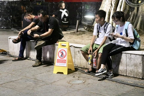 Biển báo đặt ở phố đi bộ quận Hoàn Kiếm với nội dung "Chúng tôi sẽ chụp ảnh, quay phim, hành vi xả rác bừa bãi. (Ảnh: Hồng Vĩ/TTXVN)