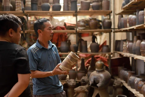 Khách hàng đến xưởng gốm của nghệ nhân Nguyễn Hồng Quang đặt hàng sản phẩm gốm Hương Canh. (Ảnh: Hoàng Hùng/TTXVN)