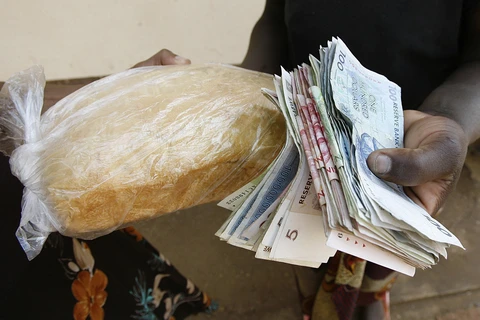 Người dân trả tiền để mua bánh mì tại Harare, Zimbabwe. (Ảnh: AFP/ TTXVN)