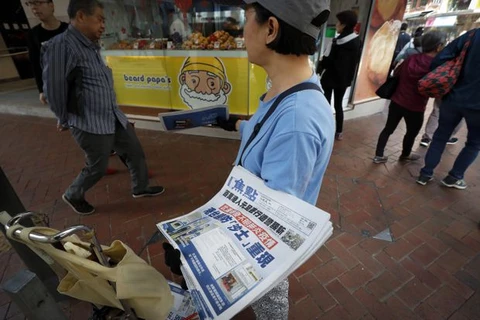 Một người bán báo trên đường phố Hong Kong với tờ báo có bài viết tiêu đề "Vũ Hán phát hiện loại virus corona mới, Hong Kong nỗ lực ngăn chặn dịch SARS trở lại" ngày 11/1. (Nguồn: theglobeandmail.com)