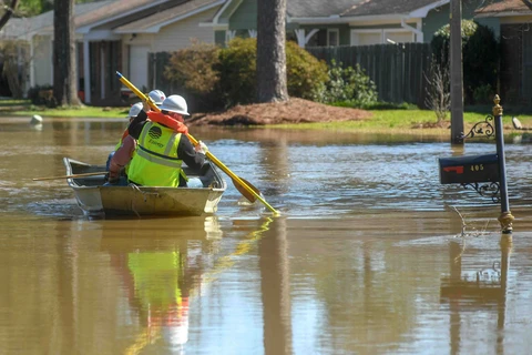 Nhân viên công ích di chuyển bằng thuyền để tắt điện trong những ngôi nhà bị ngập lụt ở Jackson, bang Mississippi.(Nguồn: nytimes.com)