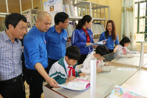 Đại diện Đoàn Thanh niên Thông tấn xã Việt Nam và Tỉnh đoàn Yên Bái giới thiệu các đầu sách cho các em học sinh. (Ảnh: Đinh Thùy-TTXVN)