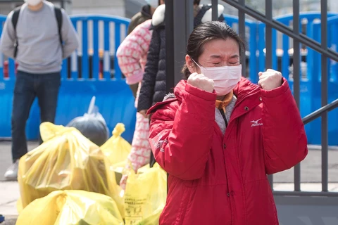 Một bệnh nhân được điều trị khỏi COVID-19 xúc động khi rời bệnh viện dã chiến ở Vũ Hán, tỉnh Hồ Bắc, Trung Quốc, ngày 8/3/2020, trước khi bệnh viện này đóng cửa. (Ảnh: THX/TTXVN)