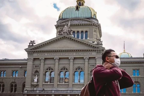 Khách du lịch đeo khẩu trang trước Tòa nhà Quốc hội Thụy Sĩ tại Bern. (Nguồn: AFP)