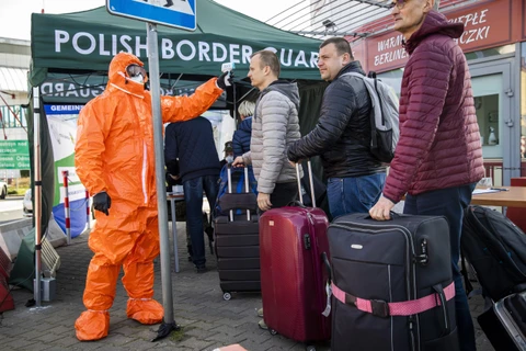 Nhân viên y tế kiểm tra thân nhiệt hành khách đi qua cửa khẩu biên giới Đức-Ba Lan, từ thị trấn Frankfurt tới Slubice nhằm ngăn ngừa dịch COVID-19 lây lan, ngày 16/3/2020. (Ảnh: AFP/TTXVN)