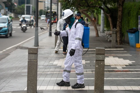 Nhân viên phun thuốc khử trùng tại địa điểm công cộng ở Jakarta, Indonesia ngày 19/3/2020, nhằm ngăn chặn sự lây lan của COVID-19. (Ảnh: THX/TTXVN)