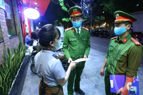 Lực lượng chức năng phường Nguyễn Du đến nhắc nhở các cửa hàng đóng cửa theo quy định. (Ảnh: Minh Quyết/TTXVN)