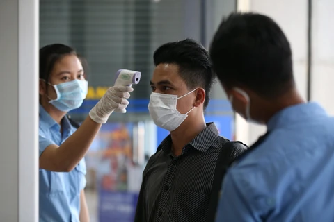 Một nhân viên kiểm tra thân nhiệt cho người dân tại Yangon, Myanmar nhằm ngăn chặn sự lây lan của dịch COVID-19, ngày 13/3/2020. (Ảnh: THX/TTXVN)