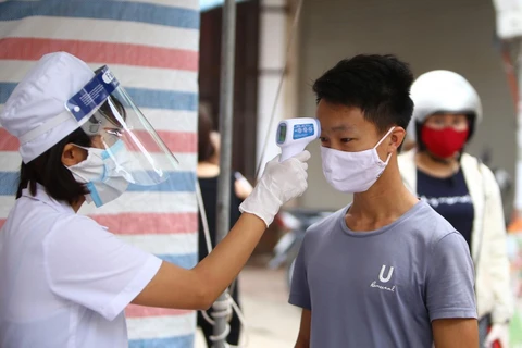 Nhân viên y tế kiểm tra, đo thân nhiệt cho người dân thôn Hạ Lôi, Hà Nội sau khi thôn được cách ly đề phòng lây nhiêm COVID-19. (Anh: Minh Quyết/TTXVN)
