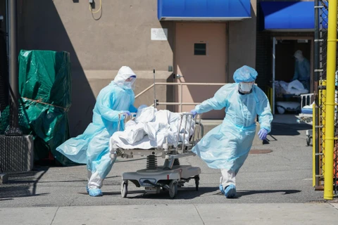 Nhân viên y tế chuyển thi thể bệnh nhân mắc COVID-19 ra nhà xác dã chiến bên ngoài một bệnh viện ở New York, Mỹ. (Ảnh: AFP/TTXVN)