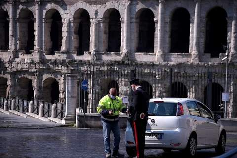 Cảnh sát Italy kiểm tra giấy tờ một lái xe tại Rome, ngày 8/4/2020 khi lệnh phong tỏa toàn quốc được thực thi nhằm ngăn dịch COVID-19. (Ảnh: AFP/TTXVN)