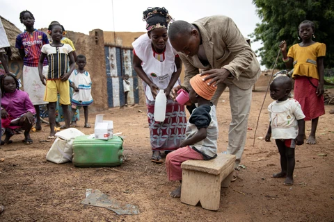 Nhân viên y tế cộng đồng giúp người dân uống thuốc phòng căn bệnh sốt rét tại Ouagadougou, Burkina Faso, ngày 20/8/2019. (Ảnh: AFP/TTXVN)