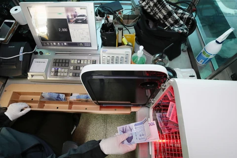 Nhân viên khử trùng tiền giấy nhằm ngăn chặn lây nhiễm COVID-19 tại một nhà ga ở Seoul, Hàn Quốc, ngày 30/3/2020. (Nguồn: THX/TTXVN)