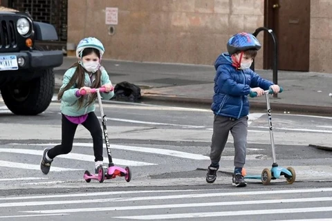 Trẻ em đeo khẩu trang chơi đùa trên đường phố ở New York trong đợt dịch bệnh COVID-19. (Ảnh: AFP)