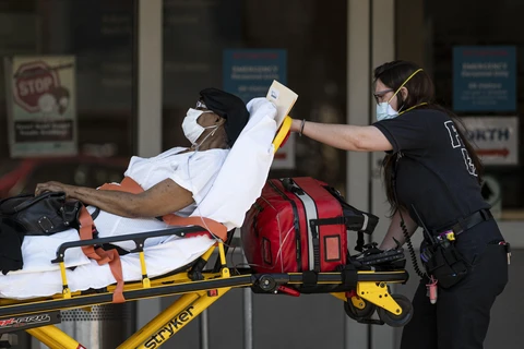 Nhân viên y tế chuyển bệnh nhân mắc COVID-19 vào một bệnh viện ở New York, Mỹ. (Ảnh: AFP/TTXVN)