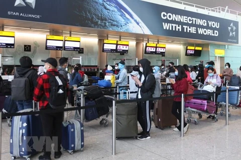 Các công dân Việt Nam xếp hàng chờ làm thủ tục lên máy bay về nước tại sân bay Heathrow. (Ảnh: Đình Thư/TTXVN)