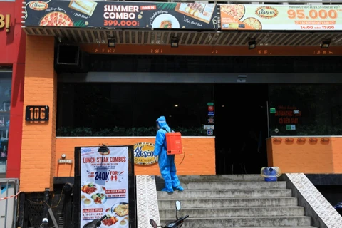 Nhân viên y tế phun thuốc tiêu độc khử trùng tại nhà hàng 106 Trần Thái Tông, Hà Nội. (Ảnh: Thành Đạt/TTXVN)