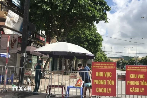 Người dân trong khu vực phong tỏa trên phố Ngô Quyền (Hải Dương) nhận thực phẩm tiếp tế tại hàng rào cách ly ngày 16/8. (Ảnh: Mạnh Minh/TTXVN)