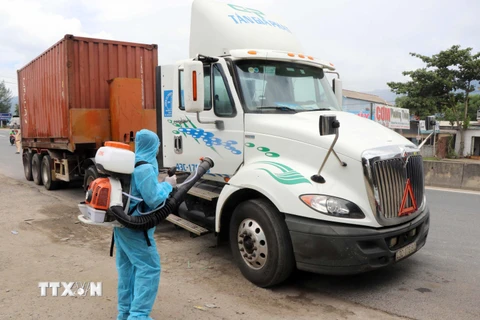 Nhân viên y tế phun thuốc khử khuẩn đối với những xe chở hàng hóa đến từ vùng dịch bệnh tại chốt kiểm soát dịch bệnh số 6 của Thừa Thiên-Huế. (Ảnh: Đỗ Trưởng/TTXVN)