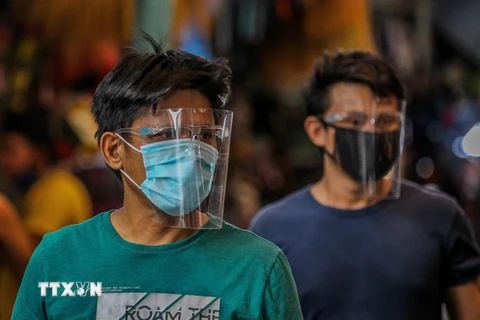 Người dân đeo khẩu trang và mặt nạ bảo hộ phòng lây nhiễm COVID-19 tại Manila, Philippines. (Ảnh: THX/TTXVN)