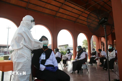 Nhân viên y tế lấy mẫu dịch xét nghiệm COVID-19 cho người dân tại Surabaya, Indonesia, ngày 22/9/2020. (Ảnh: THX/TTXVN)