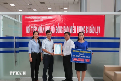 Lãnh đạo Ủy Ban mặt Trận Tổ quốc Việt Nam tỉnh Bình Dương tiếp nhận tiền hỗ trợ từ các nhà hảo tâm quyên góp. (Ảnh: Chí Tưởng/TTXVN)