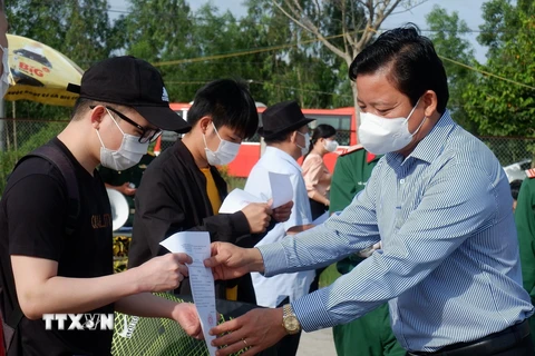 Phó Chủ tịch Ủy ban Nhân dân tỉnh Long An Phạm Tấn Hòa trao giấy xác nhận hoàn thành thời gian cách ly cho các công dân. (Ảnh: Đức Hạnh/TTXVN)